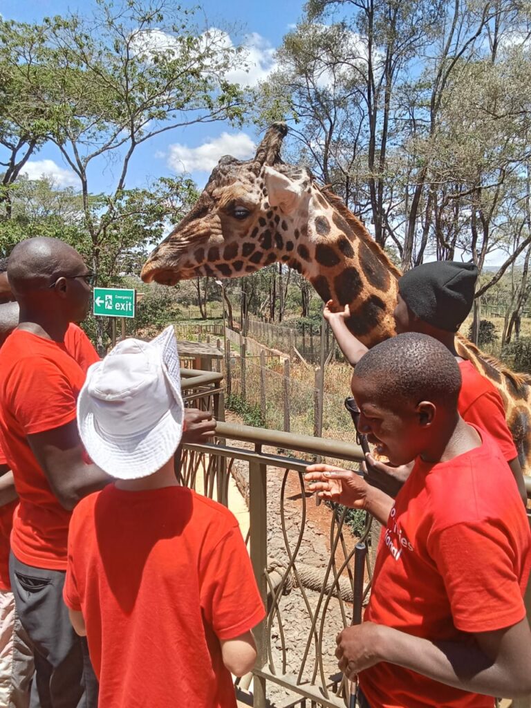 James and three students petting a giraffe